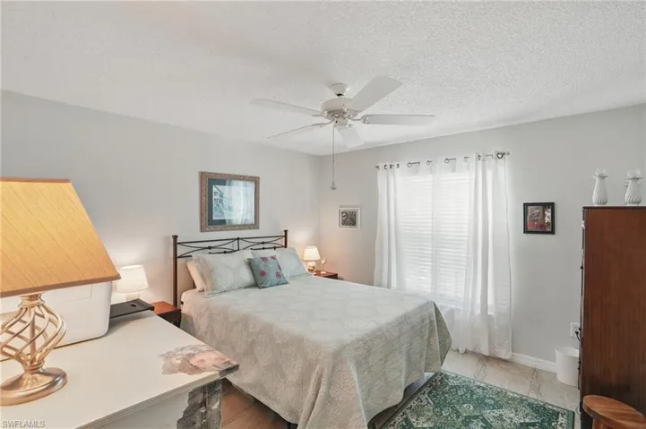 Bedroom featuring a textured ceiling, a ceiling fan, and baseboards