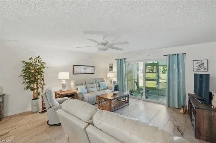 Living room with a ceiling fan and a textured ceiling