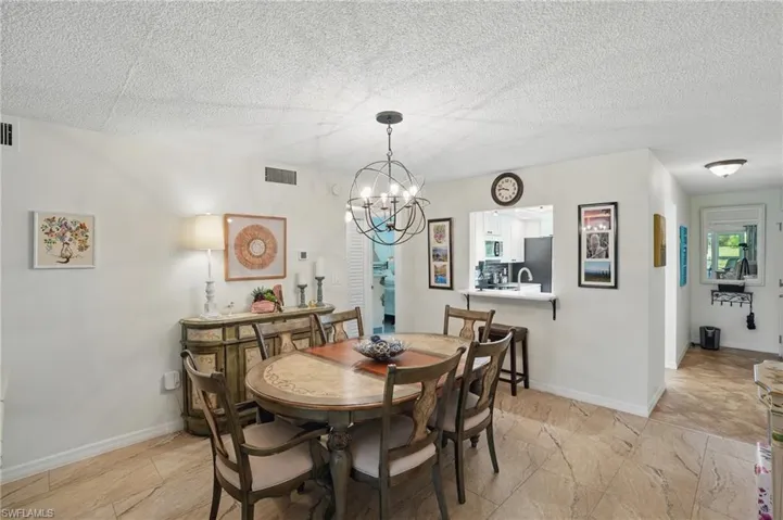 Dining space featuring a chandelier, baseboards, and a textured ceiling