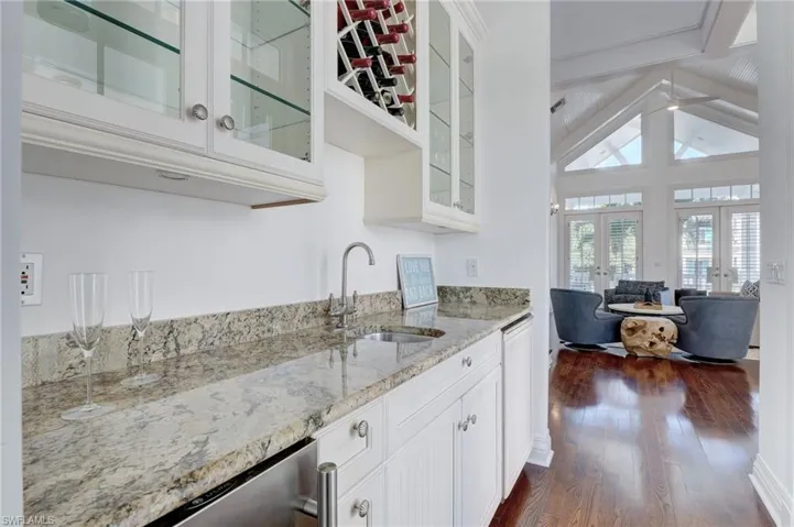 Kitchen featuring white cabinetry, lofted ceiling with beams, dark hardwood / wood-style flooring, french doors, and sink