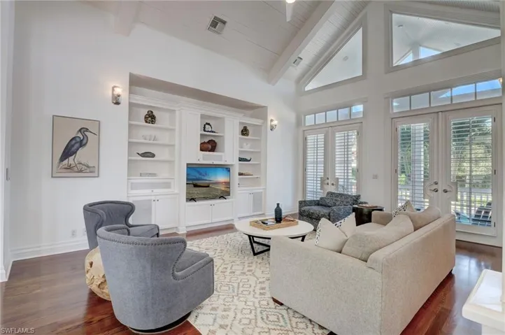 Living room with wood ceiling, high vaulted ceiling, beam ceiling, french doors, and dark hardwood / wood-style floors