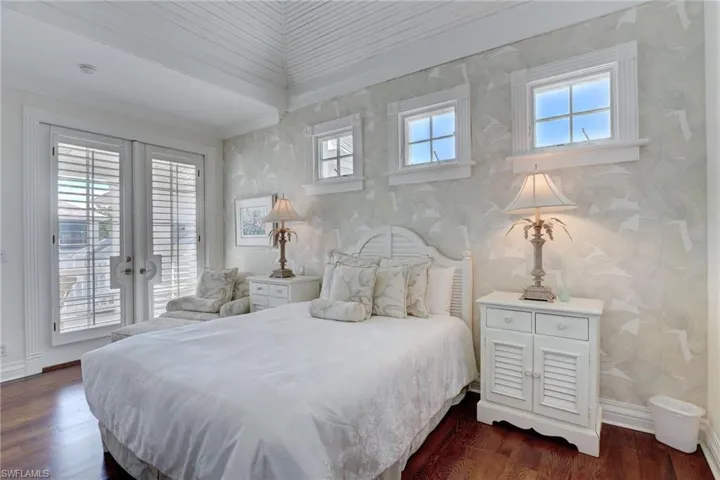 Bedroom featuring multiple windows, dark wood-type flooring, and french doors