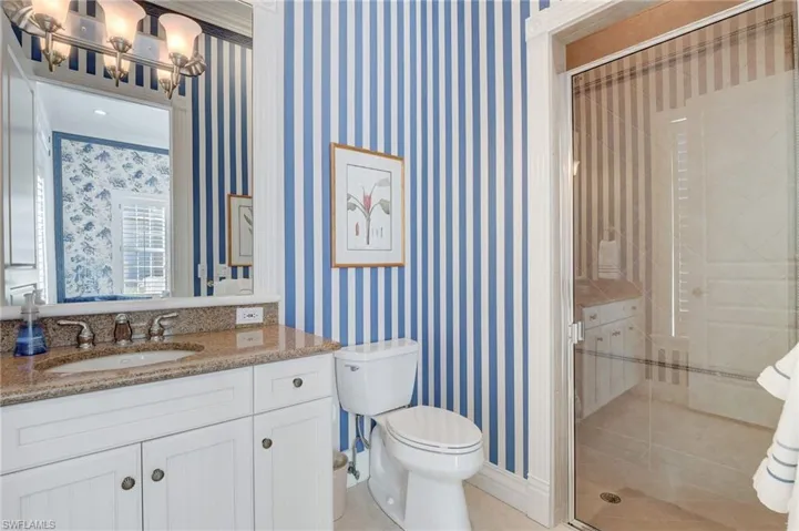 Bathroom with ornamental molding, vanity, toilet, and a shower with door