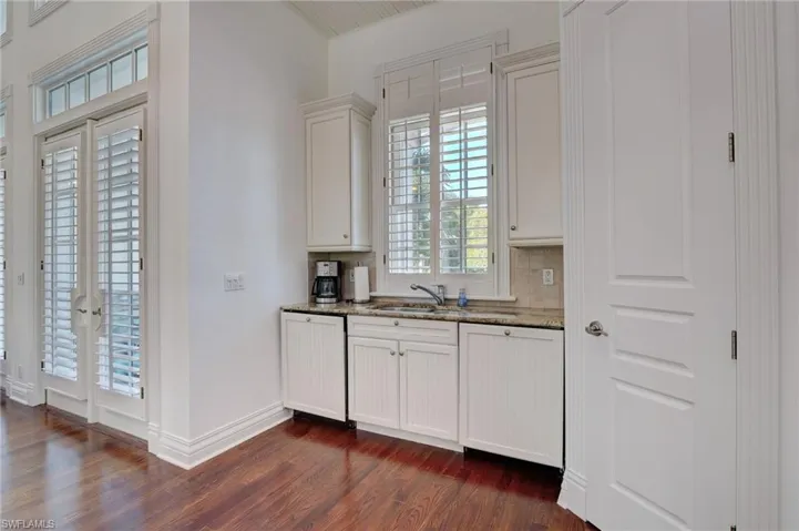 Kitchen with dark stone counters, dishwasher, sink, white cabinetry, and dark hardwood / wood-style flooring