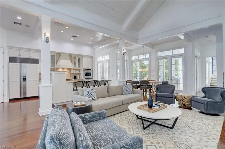 Living room with wood-type flooring, ornate columns, and high vaulted ceiling