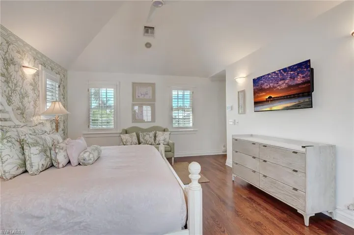 Bedroom with multiple windows, lofted ceiling, and dark hardwood / wood-style floors