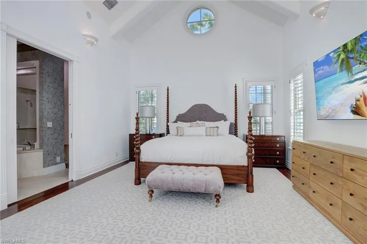 Bedroom featuring hardwood / wood-style flooring, beam ceiling, multiple windows, and high vaulted ceiling