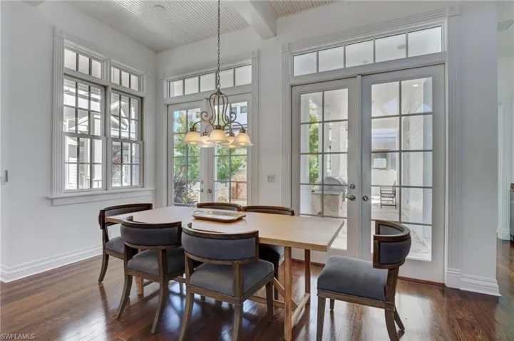 Dining room featuring french doors, an inviting chandelier, beam ceiling, and dark wood-type flooring