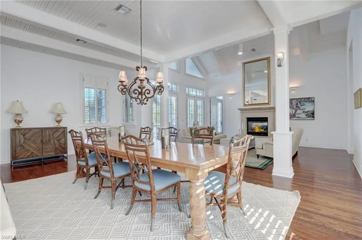 Dining space featuring vaulted ceiling with beams, decorative columns, a chandelier, and hardwood / wood-style flooring
