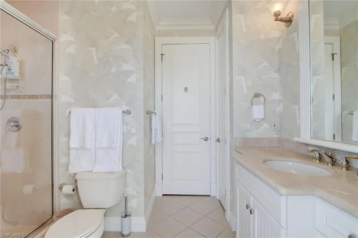 Bathroom featuring a shower with door, crown molding, vanity, and toilet