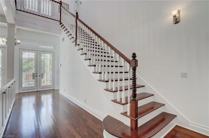 Staircase with french doors and hardwood / wood-style floors