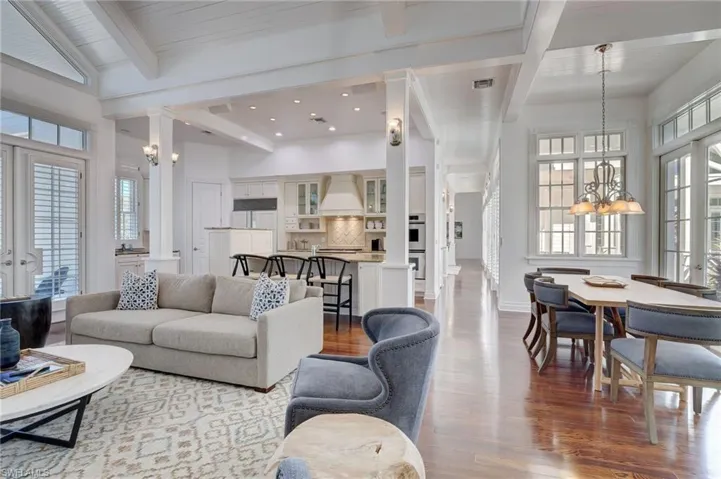 Living room featuring beamed ceiling, a notable chandelier, decorative columns, and hardwood / wood-style flooring