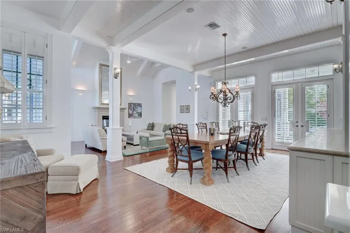 Dining area with french doors, beamed ceiling, hardwood / wood-style floors, and an inviting chandelier