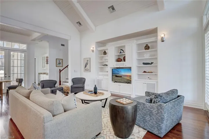 Living room with beamed ceiling, dark wood-type flooring, french doors, and high vaulted ceiling