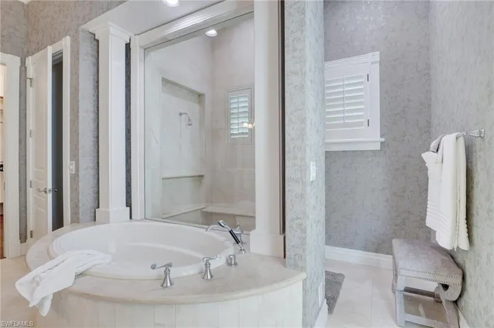 Bathroom with shower with separate bathtub and tile patterned floors