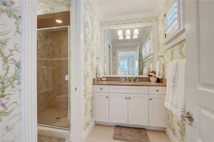 Bathroom with an enclosed shower, ornamental molding, vanity, and plenty of natural light
