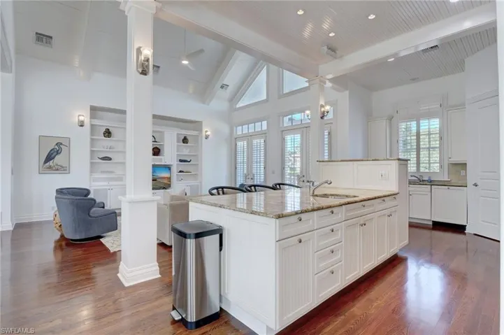 Kitchen with dark hardwood / wood-style flooring, beamed ceiling, an island with sink, and plenty of natural light