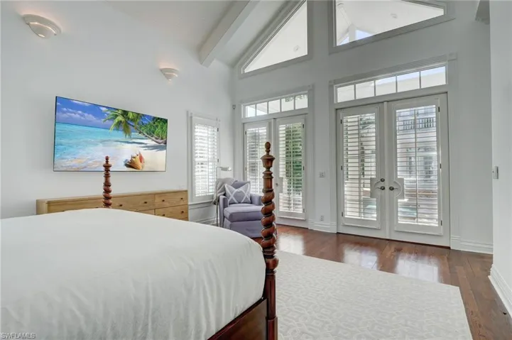 Bedroom with beamed ceiling, dark hardwood / wood-style floors, access to outside, high vaulted ceiling, and french doors