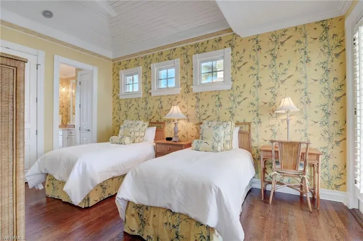 Bedroom featuring ensuite bathroom, dark wood-type flooring, and crown molding