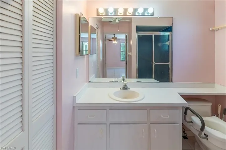 Full bathroom featuring a closet, vanity, ceiling fan, and a shower with door