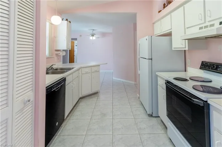 Kitchen with range with electric stovetop, under cabinet range hood, light countertops, ceiling fan, and black dishwasher