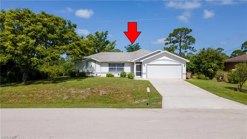 Ranch-style house with a front lawn, driveway, a garage, and stucco siding