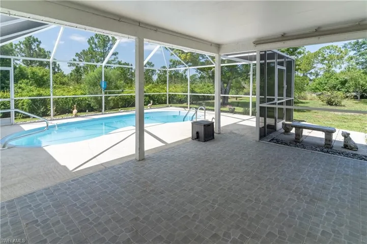 Outdoor pool featuring a patio area, a lanai, and view of scattered trees