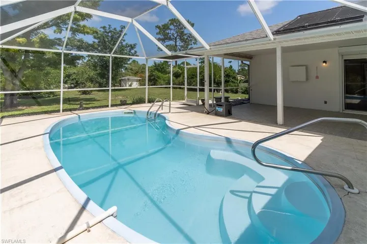Outdoor pool with a patio and glass enclosure