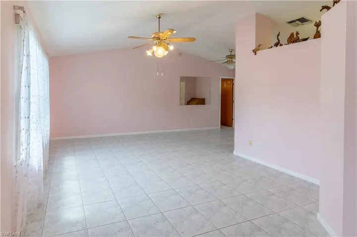 Empty room featuring vaulted ceiling, a ceiling fan, and light tile patterned flooring