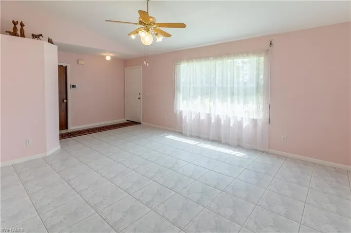 Empty room with vaulted ceiling, a ceiling fan, and tile patterned floors