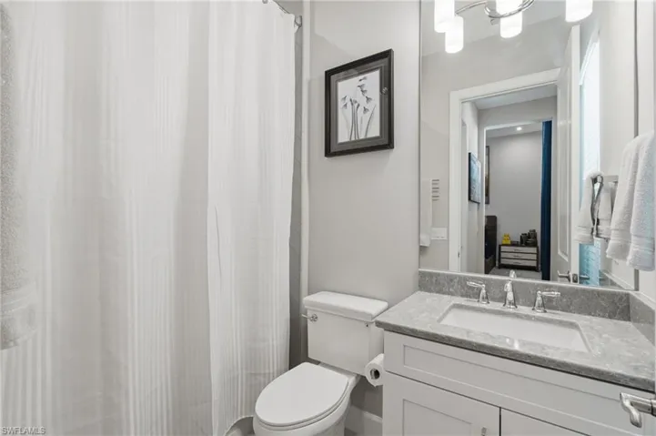 Bathroom vanity with a rectangular sink, stone countertop, and chrome faucet