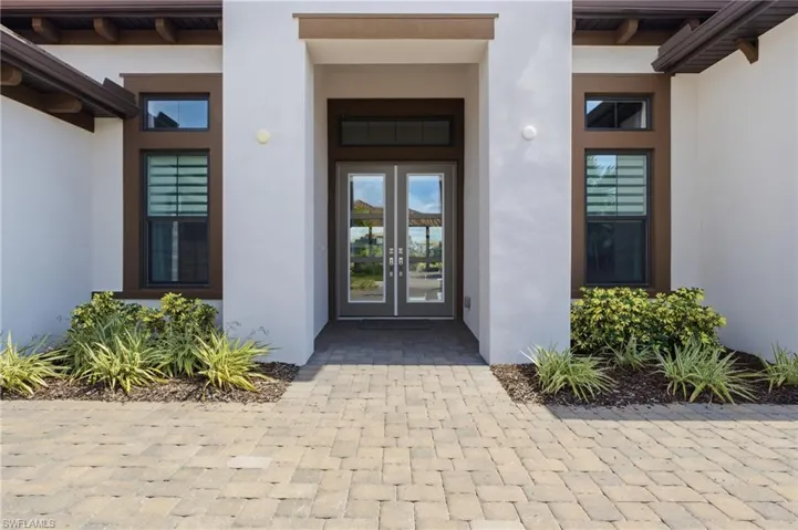 Paver driveway and walkway leading to a double-door entry with transom window