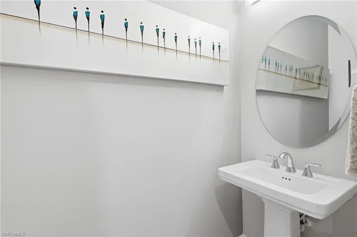 Pedestal sink with chrome fixtures and a beveled oval mirror