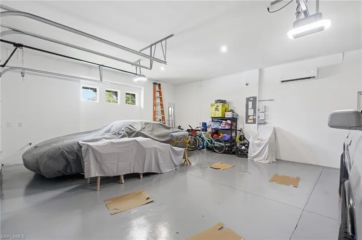 Spacious garage featuring a light gray epoxy floor coating, white walls, and multiple windows for natural light