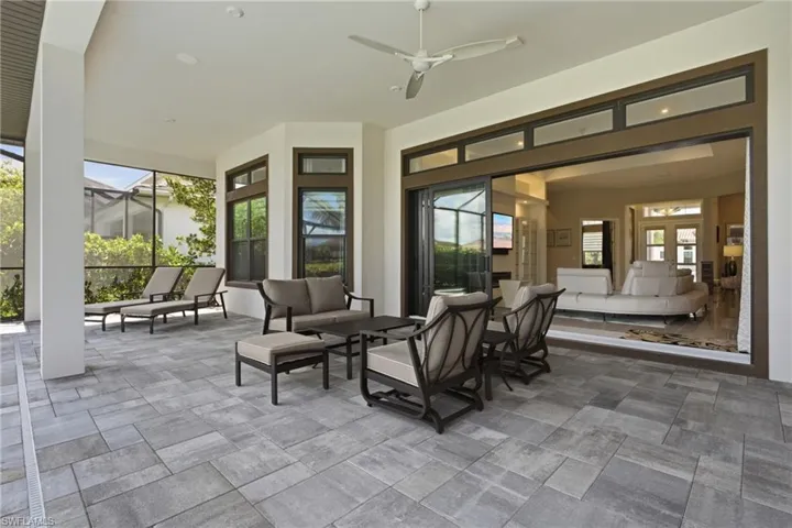 Expansive covered patio featuring large format paver flooring, a ceiling fan, and screened enclosure