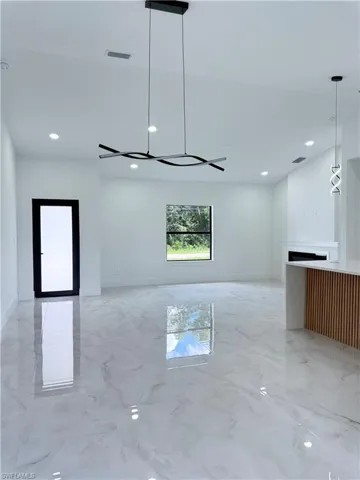 Unfurnished living room with light marble finish floors and recessed lighting