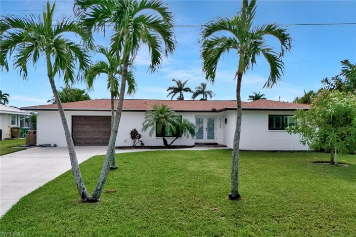 Ranch-style home with a garage, french doors, stucco siding, concrete driveway, and a front lawn