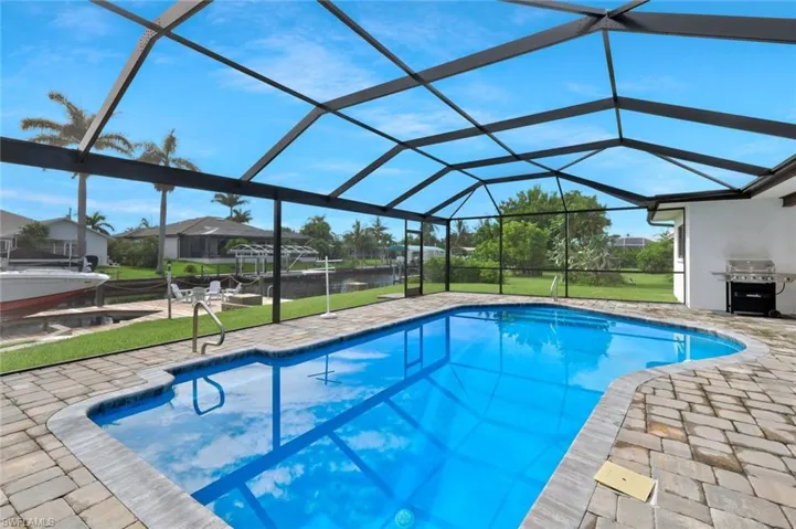 Swimming pool with a yard, a water view, and a patio area