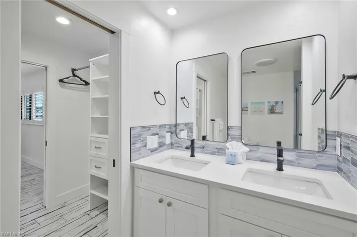 Full bath with double vanity, backsplash, a closet, recessed lighting, and light wood-style flooring