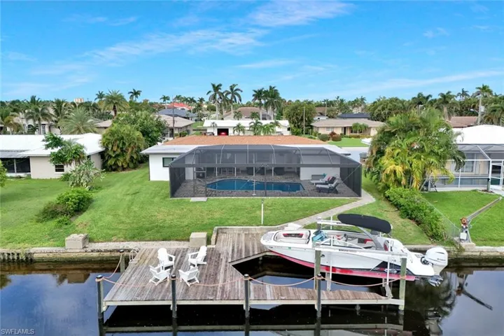 Dock area with a residential view, a water view, a sunroom, and a lawn