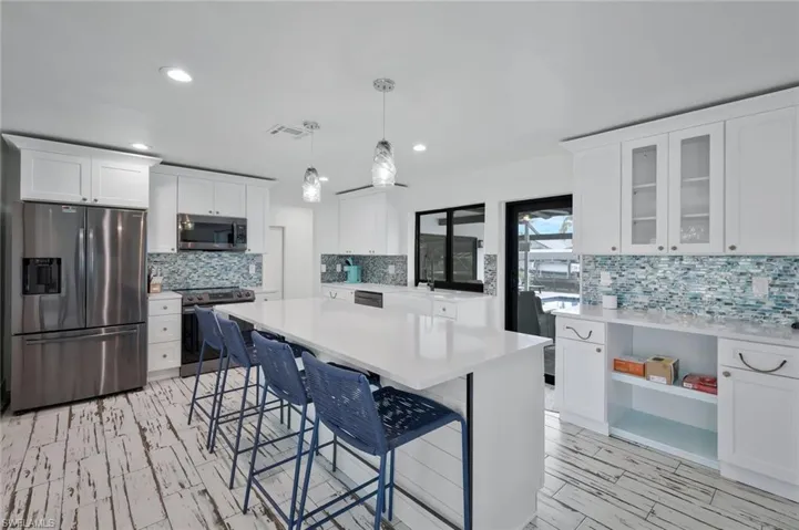 Kitchen featuring appliances with stainless steel finishes, decorative light fixtures, white cabinets, a breakfast bar, and recessed lighting