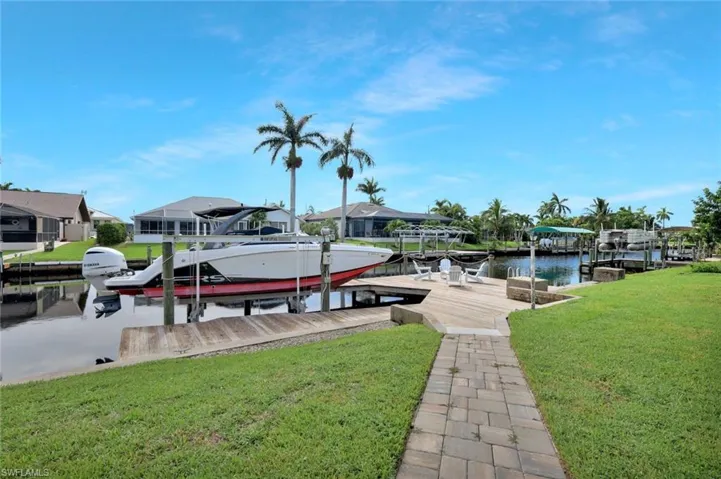 Dock area featuring boat lift, a lawn, a residential view, and a water view