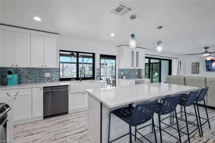 Kitchen with ceiling fan, decorative backsplash, open floor plan, white cabinetry, and appliances with stainless steel finishes