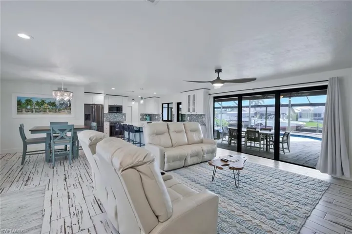 Living room with light wood-style flooring, ceiling fan, and recessed lighting