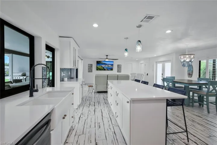 Kitchen with white cabinets, a kitchen breakfast bar, recessed lighting, a ceiling fan, and a kitchen island