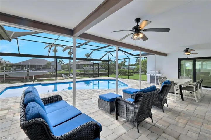 Outdoor pool featuring a patio area, a sunroom, a lanai, grilling area, and a ceiling fan