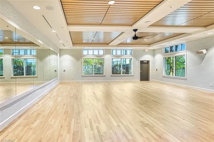 Unfurnished living room with light wood-style floors, healthy amount of natural light, wooden ceiling, and a ceiling fan