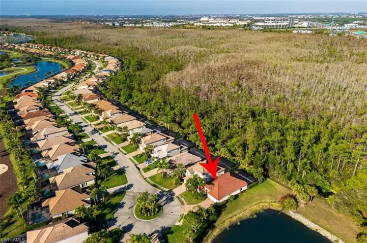 Aerial view of residential area featuring a large body of water and a heavily wooded area