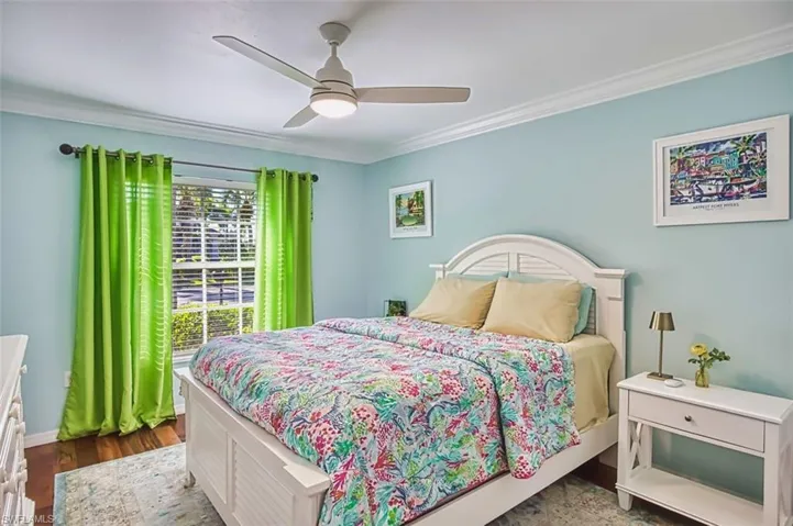 Bedroom featuring ornamental molding, a ceiling fan, and dark wood-type flooring