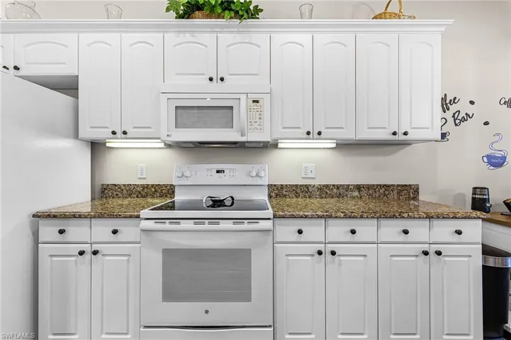 The lovely kitchen has granite countertops, white raised panel cabinets, white appliances, pantry closet off kitchen, and a breakfast nook with plantation shutters